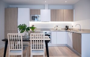 The fully equipped kitchen has an oven and induction hob, microwave, kettle, toaster, dishwasher, Nespresso machine, and a dining table with four chairs.