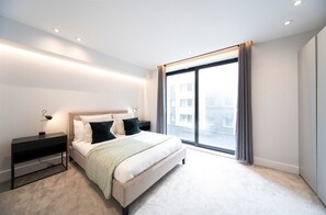 The bedroom features a floor-to-ceiling window,  a comfortable double bed (190 x 135 cm), and a spacious wardrobe.