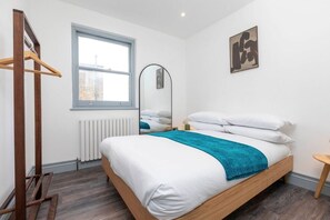 Bedroom featuring an open wardrobe, double bed (190 x 135 cm), large mirror, and bedside lamps.