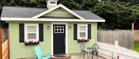 Exterior view showing brick path+patio, cottage style garden, and picket fence.