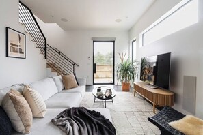The downstairs living room is furnished with a large, cozy, and comfortable sectional, an accent chair, a 65" smart flat screen TV, and integrated architectural audio with an in-wall subwoofer.