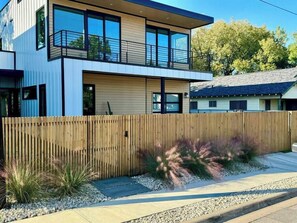 The property features a modern privacy fence with a dedicated walkway and car gate with custom landscaping.