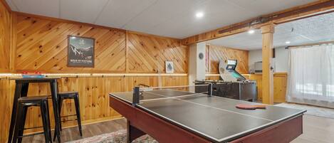 Game room has ping pong/pool table, foosball table, Arcade game, couches, TV