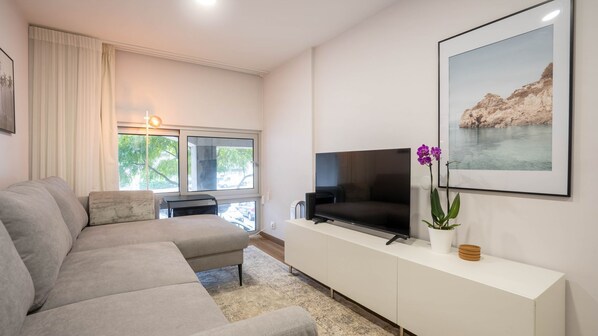 Living room with a cozy sofa and flat screen TV. #LIvingarea #LovelyStay