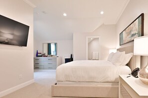 Elegant bedroom featuring a plush bed, modern furnishings, and a flat-screen TV for ultimate relaxation.