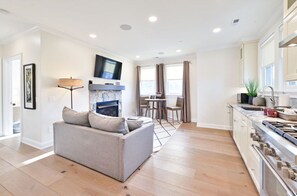 Open-concept living area featuring a modern kitchen, comfortable seating, and a cozy fireplace, perfect for relaxing and entertaining.