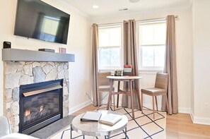 Cozy living area with a fireplace, flat-screen TV, and a small dining table, perfect for relaxing and enjoying meals.