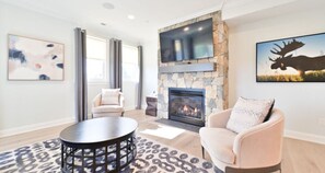 Bright living room with a cozy fireplace, stylish seating, and ample natural light for a welcoming ambiance.