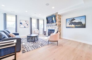 Bright and spacious living room with stylish seating, a cozy fireplace, and large windows for abundant natural light.