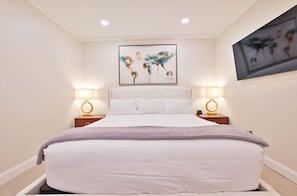 Serene bedroom with a comfortable king bed, soft lighting, and a flat-screen TV for a restful night's sleep.