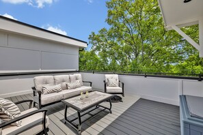 (Unit 3) 4th Floor: Private rooftop patio featuring outdoor furnishings for lounging and a Smart TV for entertainment surrounded by beautiful neighborhood views.