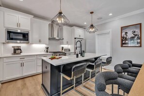 (Unit 4) 2nd Floor: Fully equipped kitchen stocked with all culinary essentials featuring Monogram stainless-steel appliances, a large kitchen island offering bar seating.