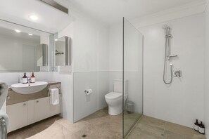 Clean and contemporary bathroom featuring a rain shower, wide vanity, and fresh white finishes.