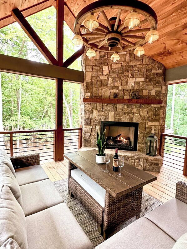 Back porch w/ gas fireplace, L-shape sofa, ottoman and dining table. Idilic