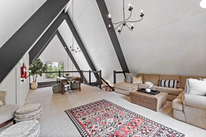 Living room 2: Dynamic loft space, plush l-shaped couch, carpet, 55” smart TV, table, upper floor