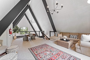 Living room 2: Dynamic loft space, plush l-shaped couch, carpet, 55” smart TV, table, upper floor