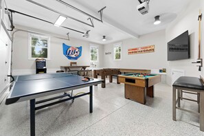 Garage  converted to a game room featuring bumper pool, ping pong, foosball bar table, TV & Pacman! 