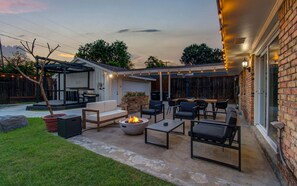 This fully furnished patio includes a conversation set, an outdoor dining table, a fire pit, and twinkling string lights to create the perfect backyard ambiance.