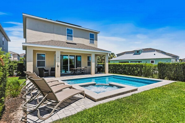 Relax in the sunlit private backyard featuring a pristine pool and comfortable lounging chairs.