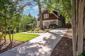 Welcome home to serenity: A tranquil retreat nestled amidst lush green lawns and shaded by majestic trees, with a driveway inviting you to your sanctuary.