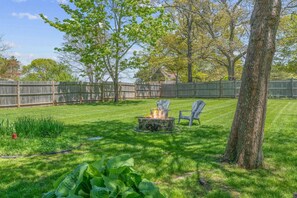 Huge fenced-in backyard with a grill, outdoor shower, fire pit, and plenty of seating.