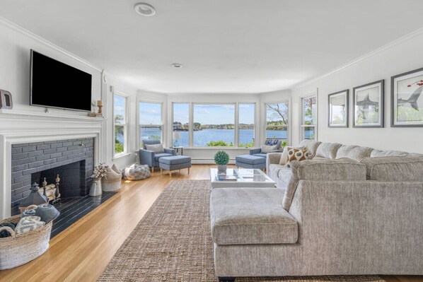 Cozy & spacious living room with a Smart TV, fireplace, and a breathtaking waterfront view.