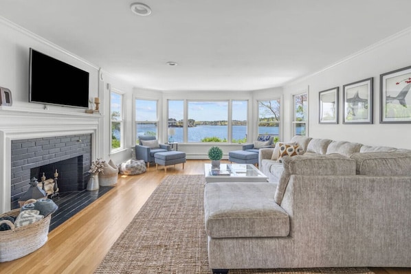Cozy & spacious living room with a Smart TV, fireplace, and a breathtaking waterfront view.