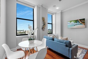 Bright and inviting living room featuring a large sofa, flat-screen TV, and plenty of natural light.
