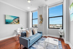 Bright and inviting living room featuring a large sofa, flat-screen TV, and plenty of natural light.