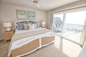 Unwind in luxury in this Revisions of Wilmington-designed bedroom, boasting a plush king bed and Bramble furnishings, where every detail is meticulously crafted to complement the mesmerizing ocean backdrop.