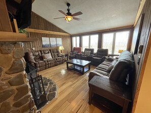 Cozy up in our rustic living room, featuring plush seating, panoramic windows, and a classic stone fireplace.