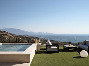An outdoor build in whirlpool is featured next to the pool.