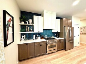 Gourmet kitchen with gas stove, large refrigerator, dishwasher, and complete set up of dishes, glassware, etc.