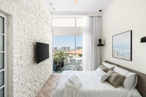 The lower floor bedroom features a stunning imported European brick wall, a ceiling fan, and an overall calm and warm design.