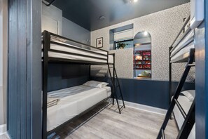 Bedroom with bunk beds, a patterned wallpaper wall, and a window with a view of street.