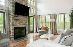 Elegant living room with a stone fireplace, modern decor, and expansive windows that bring the beauty of the outdoors inside.