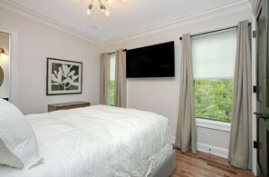 Cozy bedroom featuring a plush bed, modern decor, and large windows offering serene views of the surrounding landscape.