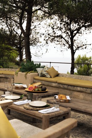 Breakfast spread with fresh fruits, overlooking a pine tree and the Adriatic.