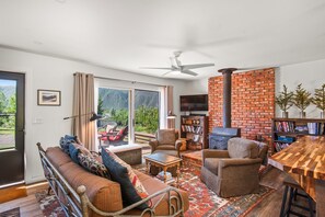 Open air living, dining, and kitchen with wood-burning fireplace and cozy seating.