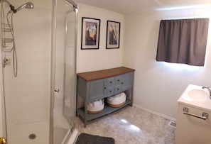 Bathroom with shower and watkins shampoo, conditioner, and body wash. No tub