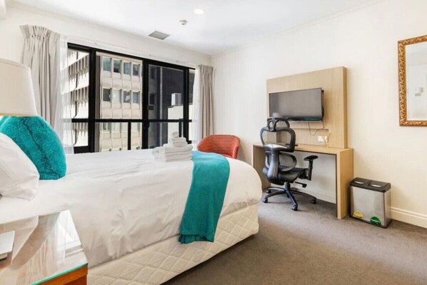 The Queen bed has lovely pops of turquoise in the throw and cushions. Relax and watch TV after a busy day.Please note: there is no desk chair.