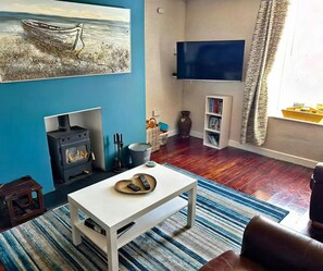 Sitting room with, sofa, armchair, coffee table, fireplace with woodburner