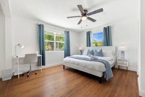 Master bedroom featuring a king bed, a TV, a work desk and an attached bathroom.