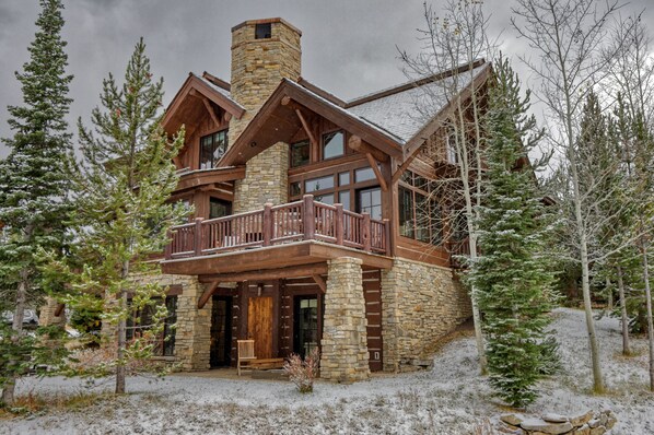Exterior of house showing a large deck with outdoor fireplace. Big views!