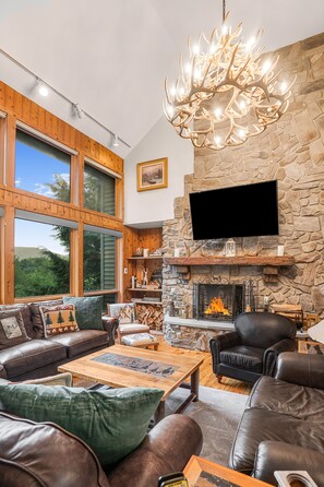 Living room with leather seating, custom tables, and stunning antler chandelier.