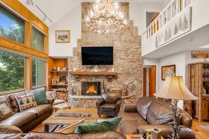 Living room has cathedral ceiling, soaring stone, and wood burning fireplace.