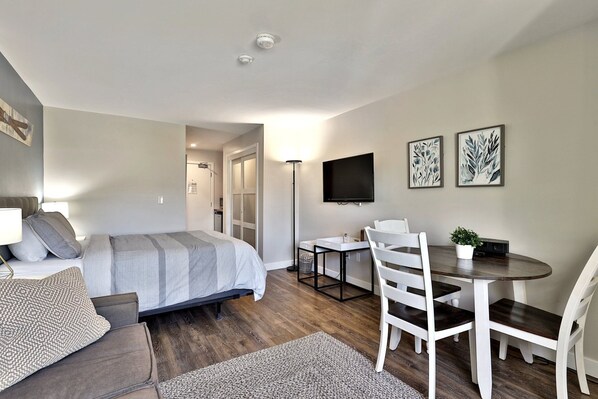 Hotel-style studio condo at Killington Center Inn & Suites, your perfect retreat for a mountain getaway in Vermont. Features a queen bed and a sleeper sofa, for up to 4 guests. A small table with chairs provides a cozy dining or work area.