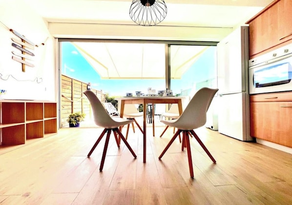 Cet espace lumineux invite à la convivialité. La table, bien que compacte, peut s'étendre pour accueillir plus de convives. L'accès direct à la terrasse promet de délicieux repas en extérieur sous le store pour se protéger du soleil.