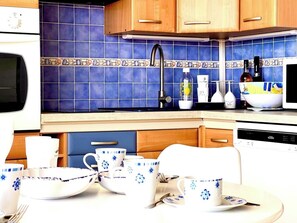 Cette cuisine rétro avec ses carreaux bleus évoque une ambiance conviviale, idéale pour cuisiner et partager. Profitez d'un espace fonctionnel avec un lave-vaisselle intégré, parfait pour un séjour sans tracas.