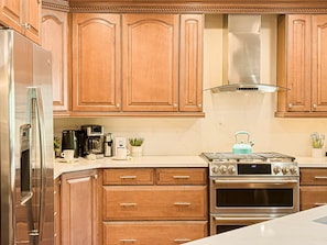 Fully equipped kitchen with 6-burner gas range and double ovens, GE refrigerator with water and ice on the door